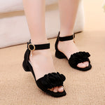 Sandales élégantes à talon noires avec détails fleuris et fermeture à scratch.