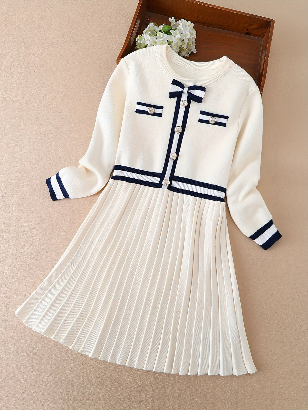 Elegant white pleated dress with navy accents and round neckline, British-inspired style for girls.
