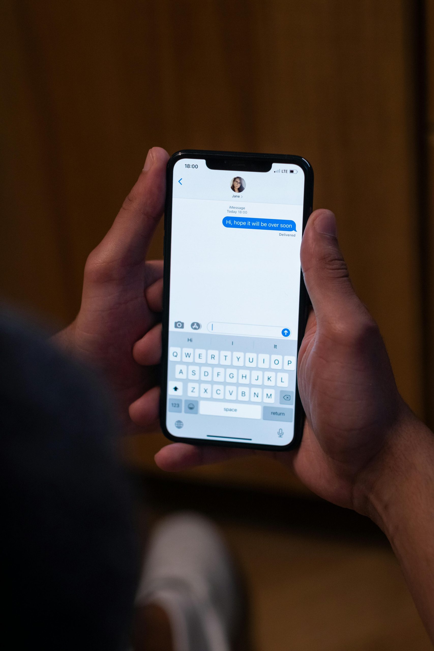 Close-up de mains en train d'envoyer un message sur un smartphone en intérieur, illustrant la communication moderne.