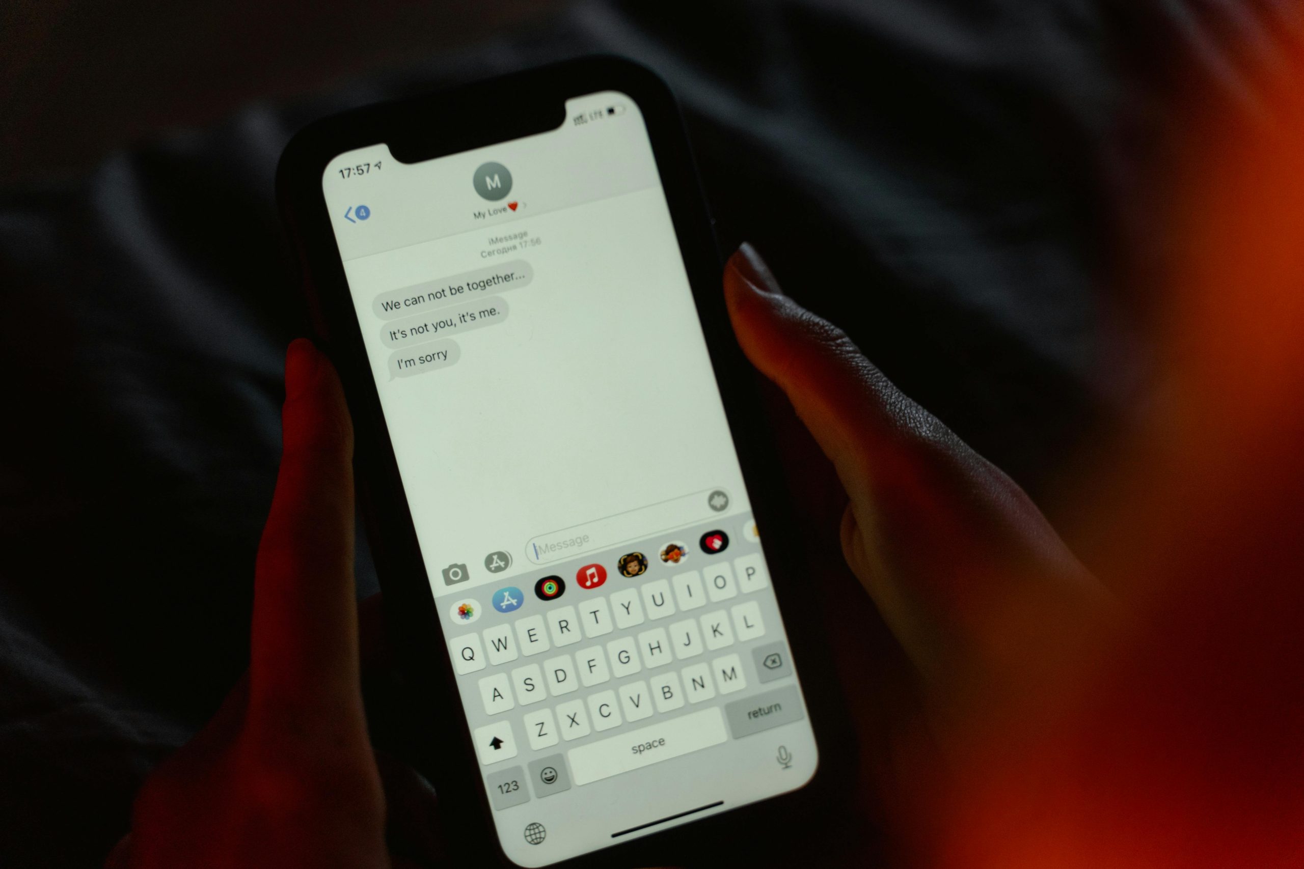 Close-up d'un message de rupture sur l'écran d'un smartphone, tenu dans des mains, évoquant des émotions.