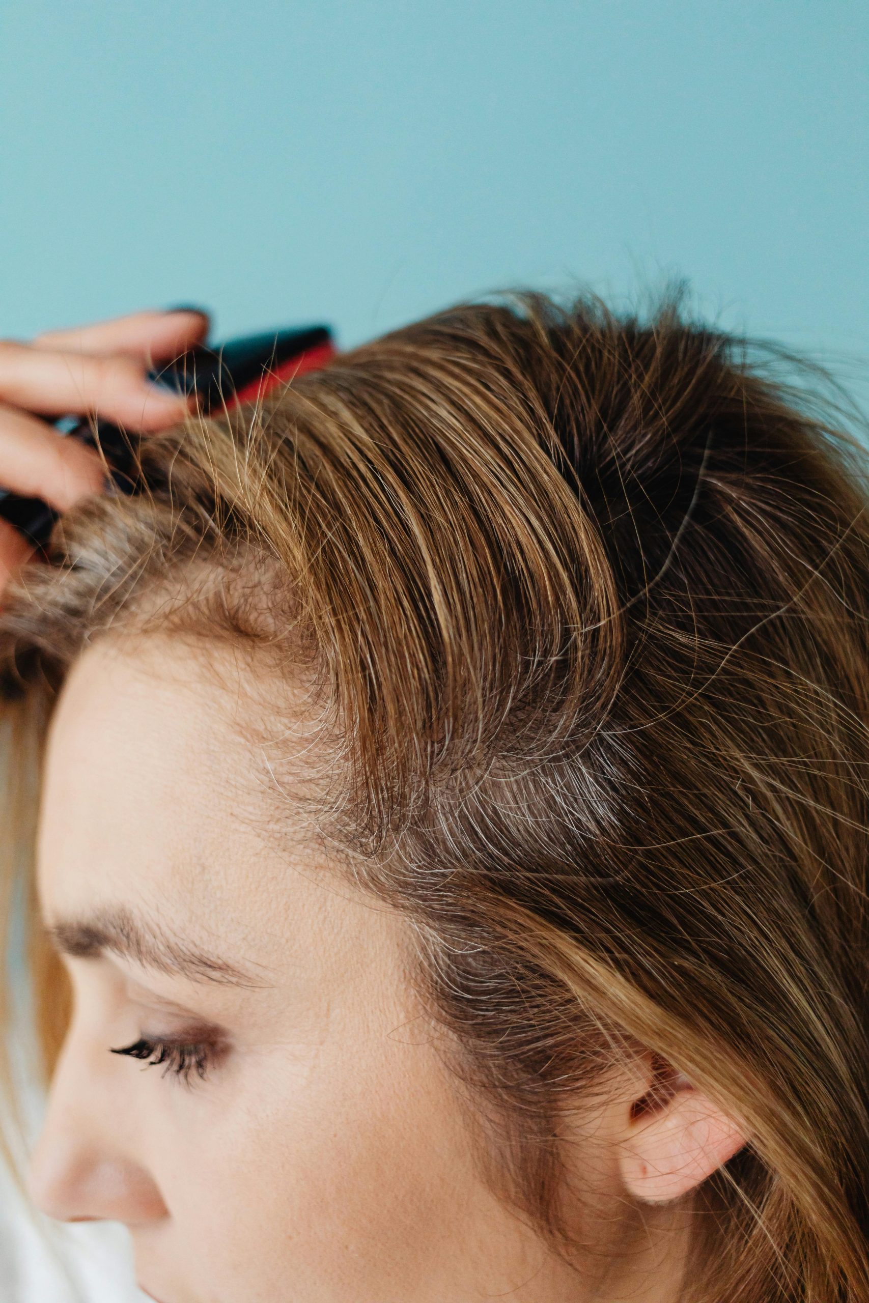 Close-up of a woman brushing her hair against a blue background in a studio setting. Gros plan d'une femme se brossant les cheveux sur un fond bleu dans un décor de studio.