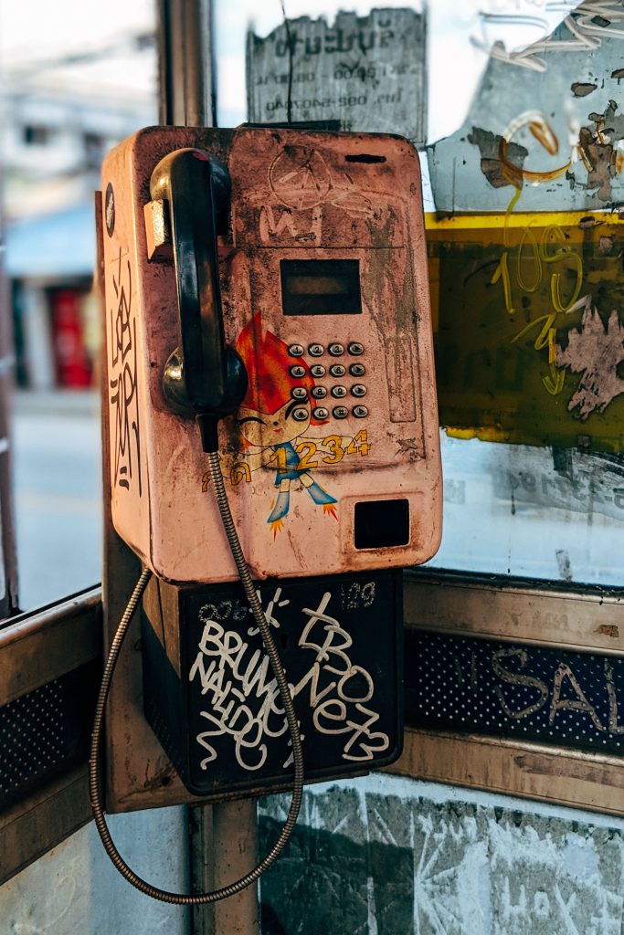 A retro phone booth with graffiti and urban decay creating a nostalgic vibe. Une cabine téléphonique rétro avec des graffitis et une décadence urbaine créant une ambiance nostalgique.