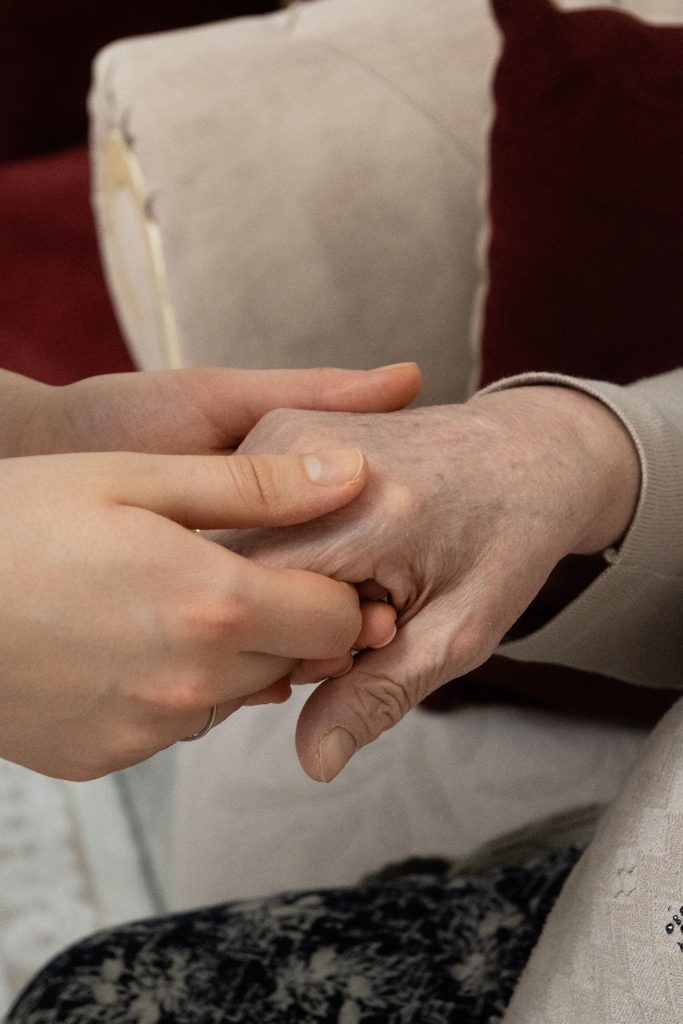 A younger person holds a senior adult's hand, symbolizing care and support. Un jeune adulte tient la main d'une personne âgée, symbolisant le soin et le soutien.