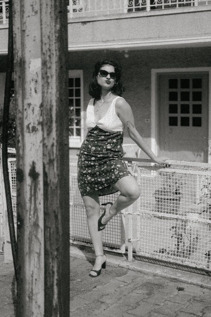 Stylish woman poses in an outdoor setting, exuding classic vintage charm. Une femme élégante pose dans un cadre extérieur, dégageant un charme vintage classique.