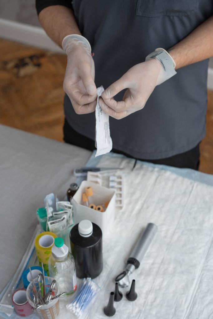 Close-up of a healthcare worker handling sterile medical tools on a prepared workstation. Gros plan d'un professionnel de santé manipulant des outils médicaux stériles sur un poste de travail préparé.