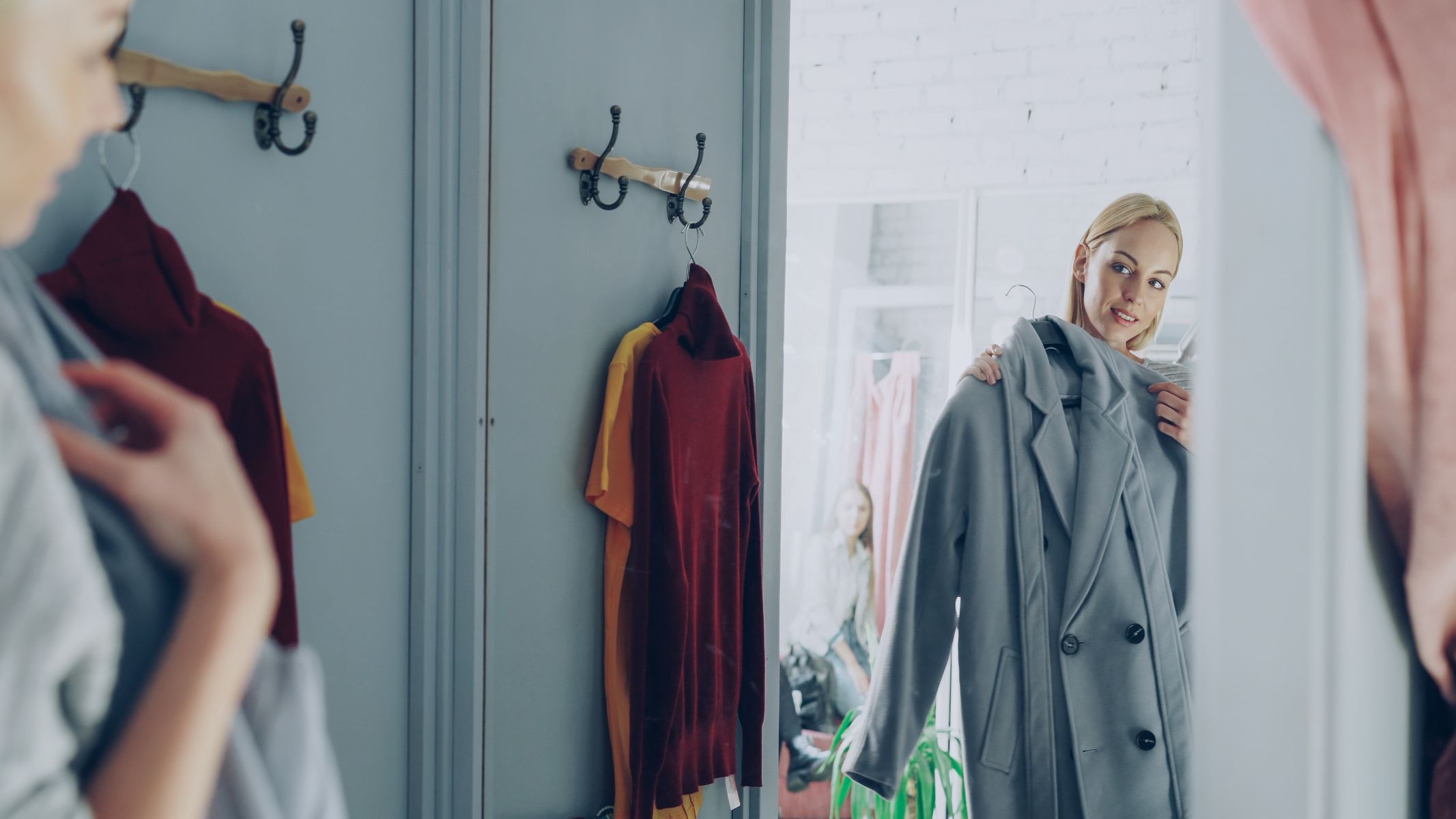 Femme essayant un manteau devant un miroir