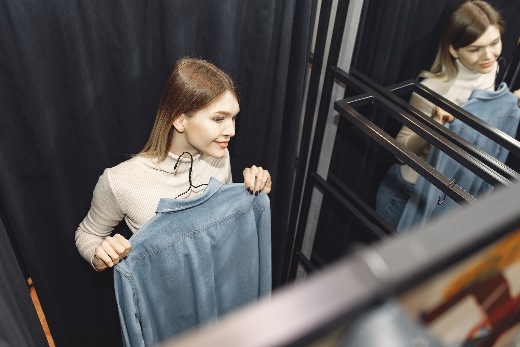 Femme essayant un vêtement en cabine d'essayage